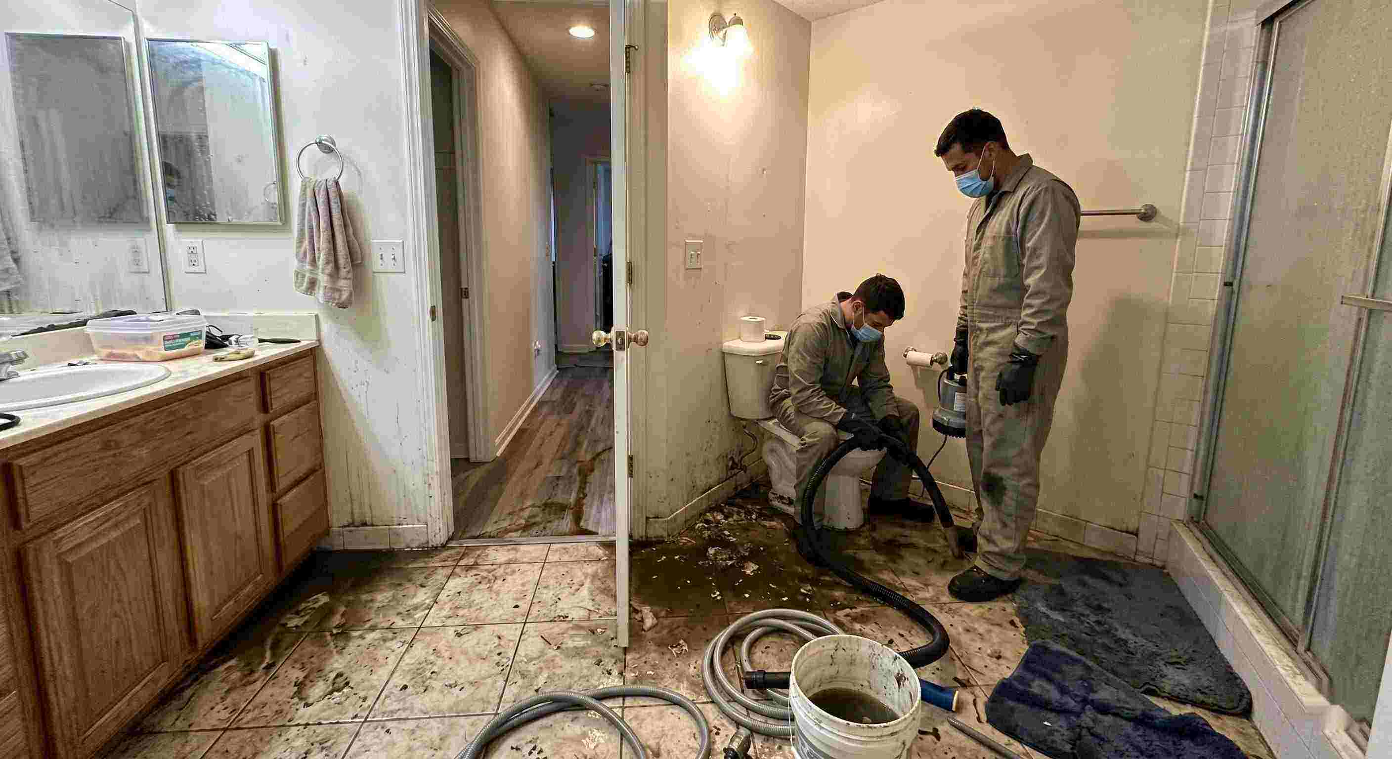 Septic tank backup cleanup in Cincinnati bathroom with technicians removing contaminated water and sanitizing affected areas