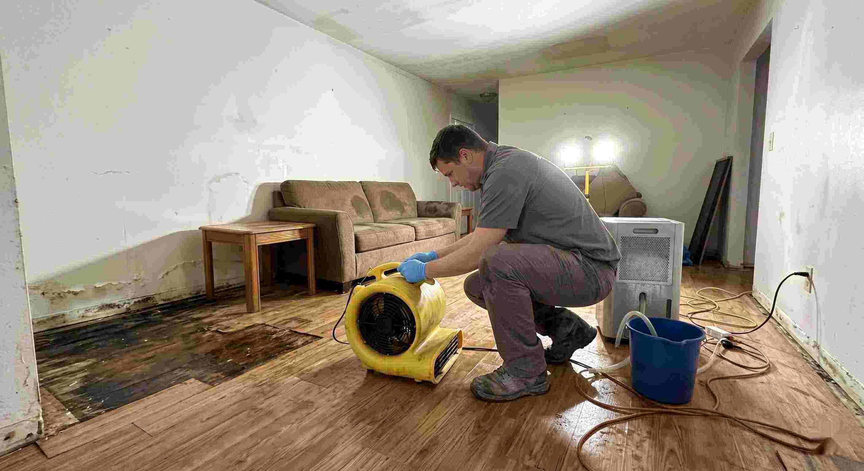 Trusted water damage restoration technician drying wet floors with equipment during cleanup process in Fairfield